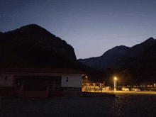 a dark landscape with mountains and a building in the foreground