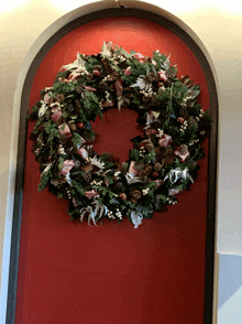 a christmas wreath hangs on a red wall