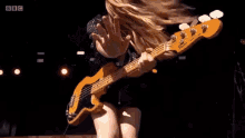 a woman in a black dress is playing a bass guitar on stage .