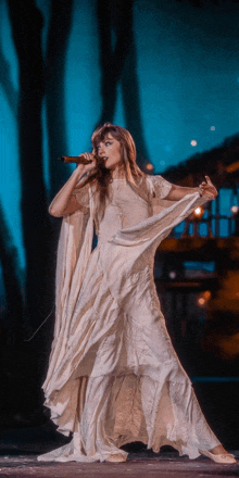 a woman in a white dress sings into a microphone