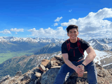 a man sitting on top of a mountain wearing a black shirt that says ' columbia ' on it