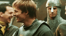 a man in a knight 's armor is laughing while standing next to two other men .