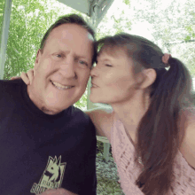 a woman kisses a man wearing a black shirt that says ryan 's books