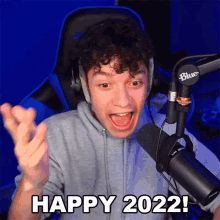 a man sitting in front of a microphone with his mouth open and says happy 2022