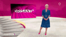 a woman in a blue dress is standing in front of a bright pink sign that says brisanti