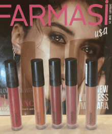 a row of liquid lipsticks are lined up in front of a farmasi usa magazine