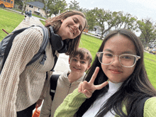 a girl giving a peace sign while standing next to a boy and another girl