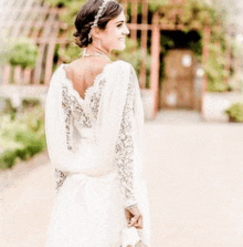 a woman in a white wedding dress is standing in front of a building .