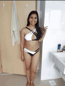 a woman in a bikini stands in a bathroom next to a sink