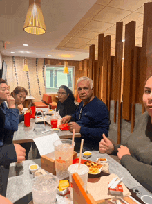 a group of people are sitting at a table in a restaurant eating