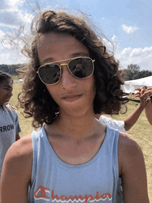 a man wearing sunglasses and a champion tank top