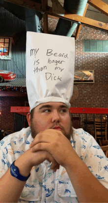 a man wearing a chef 's hat with a note on it that says " my beard is longer than my dick "