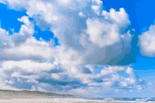 a beach with a blue sky and white clouds in the background