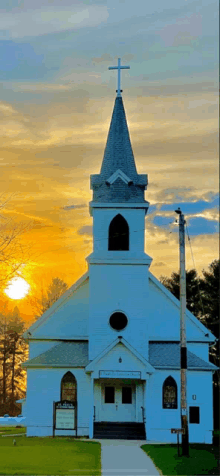 a white church with a steeple and a cross on top of it