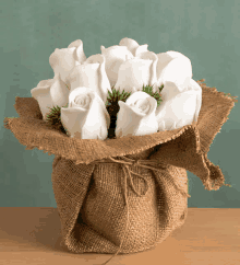 a bunch of white roses in a burlap bag