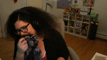 a woman wearing headphones and glasses is sitting in front of a shelf with a sign that says swagarita