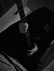 a black and white photo of a person playing a guitar with a shirt that says ' a ' on it