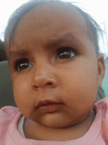 a close up of a baby 's face in a pink top