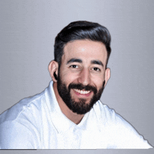 a man with a beard wearing a white shirt smiles