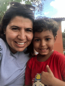 a woman and a child are posing for a picture and the boy is wearing a red shirt with a cartoon character on it