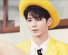 a young man wearing a yellow hat and a yellow suit .