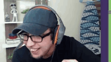 a man wearing glasses and headphones is smiling while playing a video game .