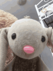 a stuffed animal with a pink nose is sitting on a bed