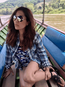 a woman wearing sunglasses sits on a boat in the water