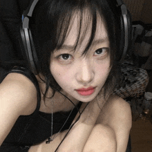 a girl wearing headphones and a necklace looks at the camera