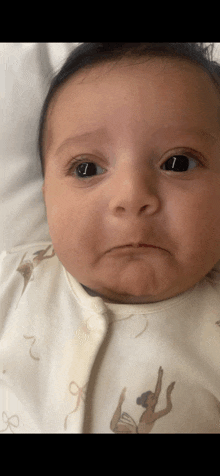 a baby is wearing a white outfit with ballerinas on it and making a funny face