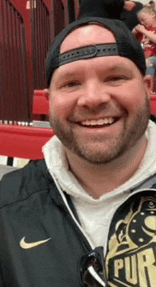 a man with a beard and a hat is smiling for the camera .