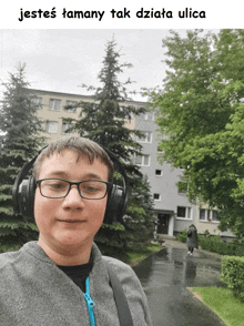 a boy wearing headphones stands in front of a building with the words jestes tamany tak dziata ulica below him