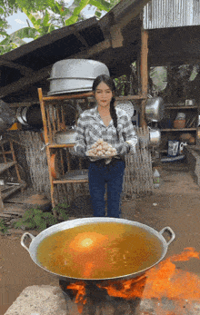 a woman in a plaid shirt is holding a tray of food in front of a large pot of liquid