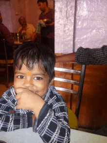 a young boy with an orange dot on his forehead is smiling