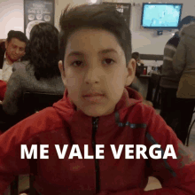 a young boy in a red jacket says me vale verga in white letters