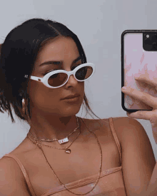 a woman wearing sunglasses takes a picture of herself