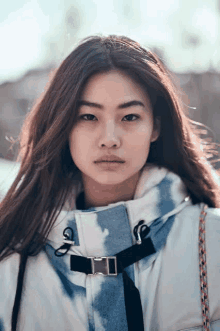 a woman with long hair is wearing a tie dye jacket and looking at the camera