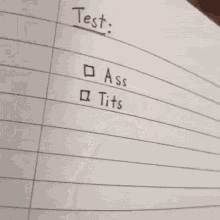 a person writing on a piece of paper that says test ass tits