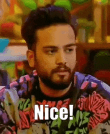 a man with a beard is wearing a colorful sweater and says `` nice ! ''