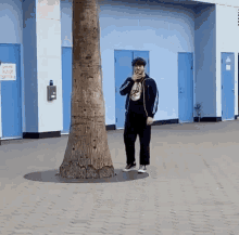 a man standing next to a tree in front of a building that has a sign that says no smoking