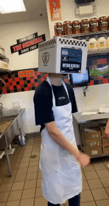 a man wearing a box on his head in front of a wall that says the original since 1983