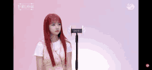 a girl with red hair is standing in front of a microphone on a pink background