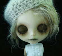 a close up of a doll 's face with her eyes closed and a hat on