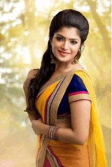 a woman in a yellow and blue blouse is smiling for the camera