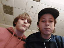 two boys are posing for a picture in front of a white tiled ceiling