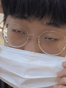 a close up of a person wearing glasses and holding a mask .