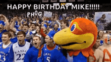 a group of people are standing in front of a mascot and a sign that says `` happy birthday mike '' .