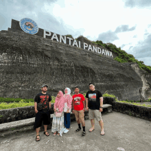 a group of people posing in front of a large sign that says pantai pandawa