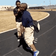 two men are standing next to each other on a track and one of them is carrying a backpack .