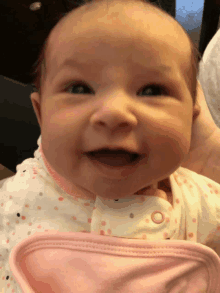 a baby in a pink and white polka dot outfit smiles